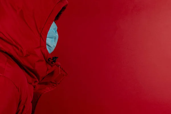 赤いジャケットの男は 赤い背景にコロナウイルスに対する保護マスクを使用しています 高いアラートの赤い色のシンボルと病気に対する標識を停止 Covid Sarsの SarsのCov ウイルス2020 — ストック写真