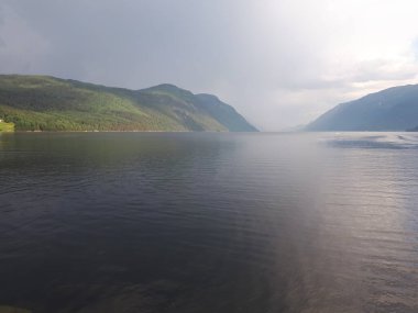 Dağları ve suyu olan puslu bir manzara.