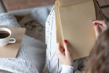 Genç bir kadın evdeki kanepeye elinde kalemle boş bir defterle yazmaya başladı. Defter boş..