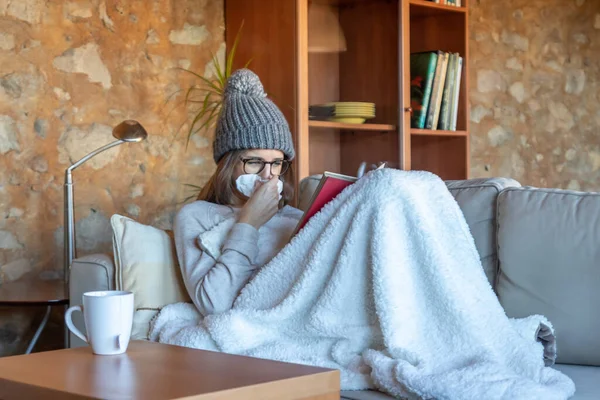 Una Joven Muy Guapa Sonándose Nariz Sofá Casa Leyendo Libro — Foto de Stock