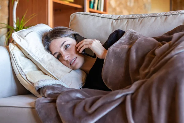 Seriöses Hübsches Mädchen Telefoniert Ausgestreckt Auf Dem Heimischen Sofa Bedeckt — Stockfoto