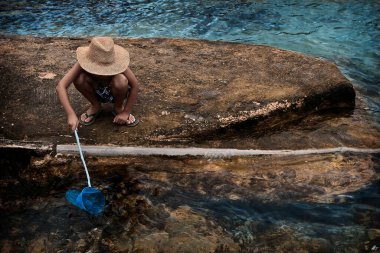 Bir çocuk balık ağı kullanarak rüyalarını yakalıyor.