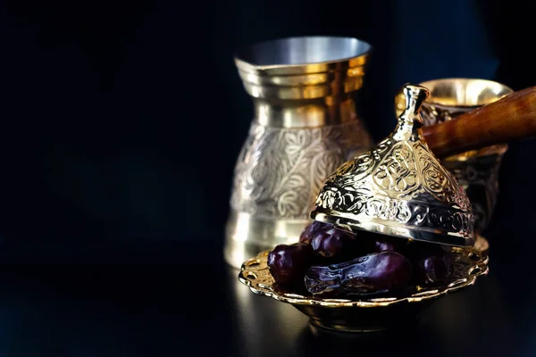 Still life with traditional luxury golden arabic coffee set with jezva, cup and dates. Dark background. Ramadan concept.