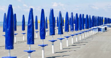 İtalya 'nın Grado şehrinde sezon başlamadan önce kapalı güneş şemsiyeli kumsal.