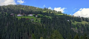 Avusturya, Carinthia 'daki LesachValley' de bir tepe yamacındaki ormandaki dağ çiftlikleriyle panoramik manzara