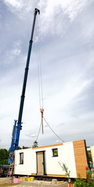 Kamyona monte edilmiş bir vince asılı prefabrik bir evin dış duvarı.