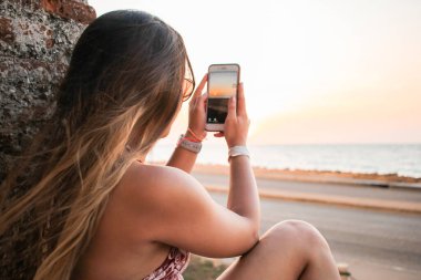 Cep telefonlu genç bir kadın selfie çekiyor.