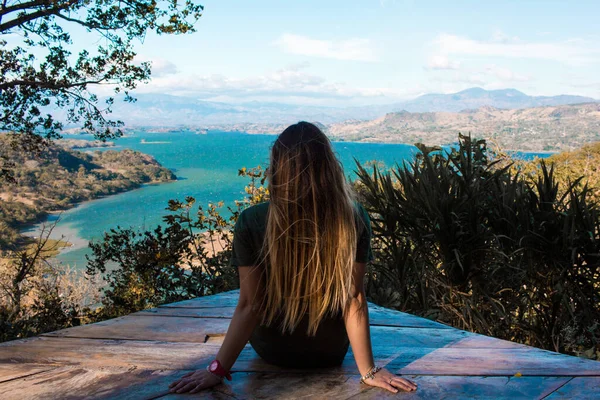 A young woman watching the scenery of a beautiful lake on a sunny day with many clouds