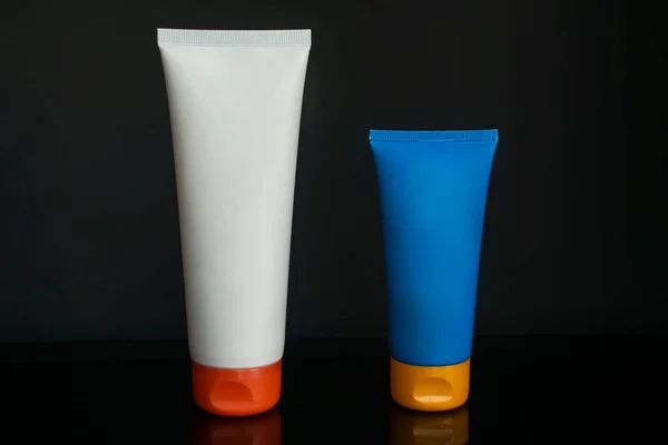 White and blue packaging for cream and lotion over black background
