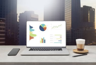 fincan kahve ve güzel iş modern ofis binaları arka plan karşı tablo üstünde hareket eden telefon ile Laptop gösteren boş ekran. teknoloji kavramı 