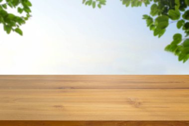 Boş ahşap masa üstü karşı yeşil yaprakları bulanıklık ve gökyüzü bokeh arka plan bulanıklık. görüntülemek için kullanılan veya ürünler reklam montaj. Doğa sesi