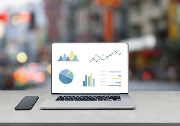 Laptop showing chart and graph and mobile phone on table against — Stock Photo, Image