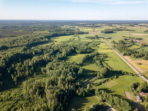 drone image. aerial view of countryside road network, cultivated fields and forest textures. latvia