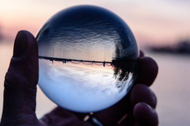 Köprü ve kristal top yansıma günbatımı sırasında. Crystal abll tutan el