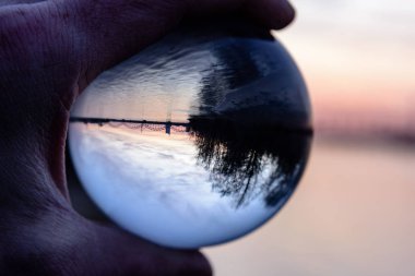 Köprü ve kristal top yansıma günbatımı sırasında. Crystal abll tutan el