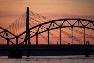 Demiryolu metal köprü siluet nehir, Daugava Riga, Letonya bulutlar ile koyu kırmızı sunet içinde üzerinde