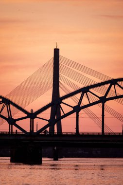 Demiryolu metal köprü siluet nehir, Daugava Riga, Letonya bulutlar ile koyu kırmızı sunet içinde üzerinde
