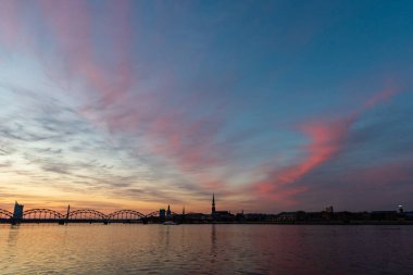 Demiryolu metal köprü siluet nehir, Daugava Riga, Letonya bulutlar ile koyu kırmızı sunet içinde üzerinde