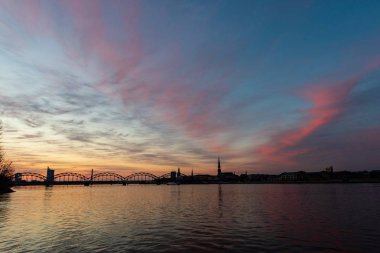 Demiryolu metal köprü siluet nehir, Daugava Riga, Letonya bulutlar ile koyu kırmızı sunet içinde üzerinde