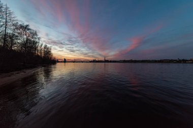 Demiryolu metal köprü siluet nehir, Daugava Riga, Letonya bulutlar ile koyu kırmızı sunet içinde üzerinde