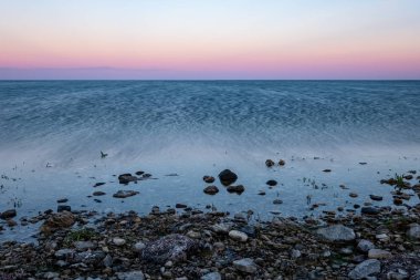 Baltık Denizi kıyısında kayalık plaj ve üzerinde dramatik gündoğumu. uzun pozlama vurdu. Estonya, Hiiumaa Adası