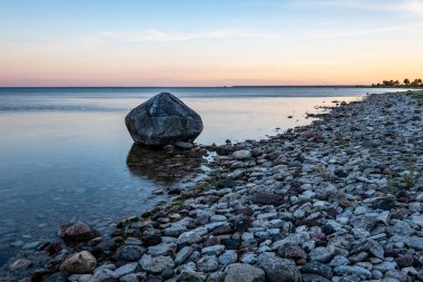 Baltık Denizi kıyısında kayalık plaj ve üzerinde dramatik gündoğumu. uzun pozlama vurdu. Estonya, Hiiumaa Adası
