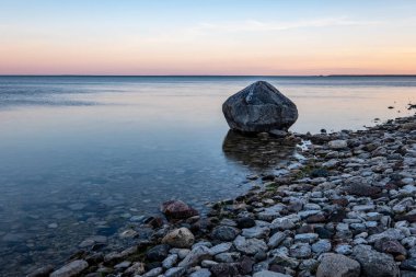 Baltık Denizi kıyısında kayalık plaj ve üzerinde dramatik gündoğumu. uzun pozlama vurdu. Estonya, Hiiumaa Adası