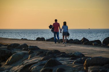brakewater denizin üzerinde zevk günbatımı insanlar. sıcak yaz gecesi, yürüyüş ve rahatlatıcı anonim kişiler. siluetleri