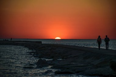 brakewater denizin üzerinde zevk günbatımı insanlar. sıcak yaz gecesi, yürüyüş ve rahatlatıcı anonim kişiler. siluetleri