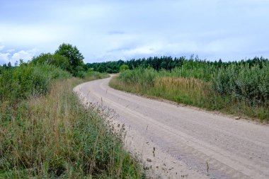 Yaz aylarında köy çakıl yol olarak kırsal orman ağaçları saran ve bulutlar gökyüzünde