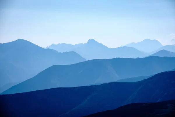 western carpathian mountain tops in  autumn covered in mist or clouds with blue cast and multidimensional lines