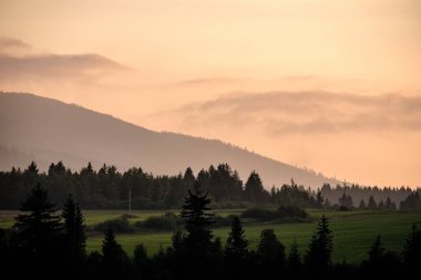 Batı Karpat Dağları'nda sisli orman manzarasına. Sisli gün batımı, Tatra uzak ufuk. Erken sonbahar Slovakya'da