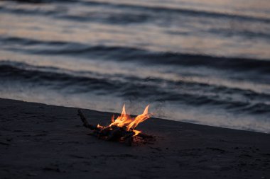 arka plan dalgalar ile gece deniz kıyısında yanan küçük ateşi. sakin akşam