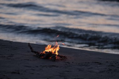 arka plan dalgalar ile gece deniz kıyısında yanan küçük ateşi. sakin akşam