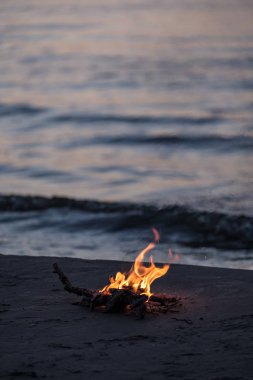 arka plan dalgalar ile gece deniz kıyısında yanan küçük ateşi. sakin akşam