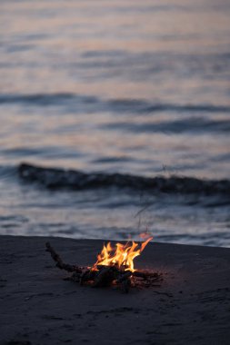 arka plan dalgalar ile gece deniz kıyısında yanan küçük ateşi. sakin akşam