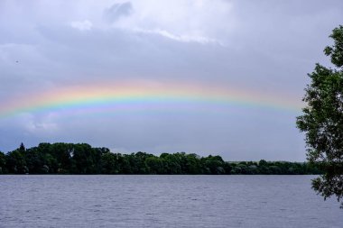 Gökkuşağının üstünde ülke alanları fırtınalı bulutlu gökyüzü göl yakınındaki 