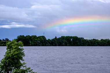 Gökkuşağının üstünde ülke alanları fırtınalı bulutlu gökyüzü göl yakınındaki 