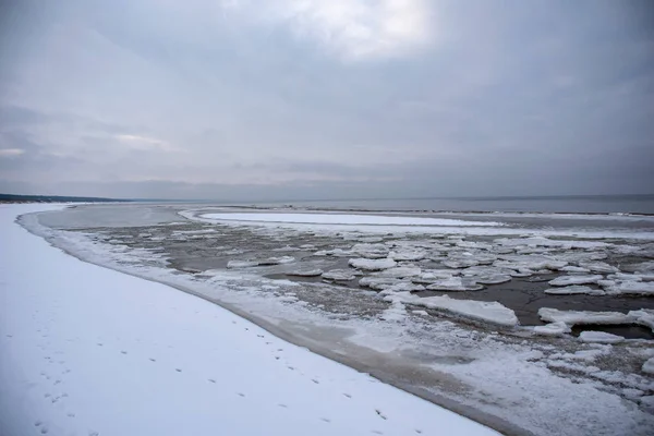 冰冻湖岸边在冬季与足迹在雪地和冰块横跨现场 — 图库照片
