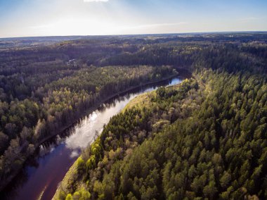 drone görüntü. alanları ve ormanları ve bulutlu bahar günü nehir su yansımalar kırsal alan hava görünümünü. Letonya