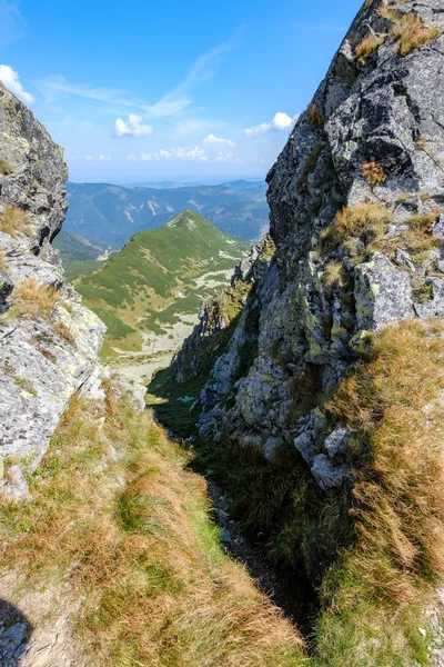 rocky mountain tops with hiking trails in autumn in Slovakian Tatra western Carpathian with blue sky and late grass on  hills. Empty rocks in bright daylight, far horizon for adventures.