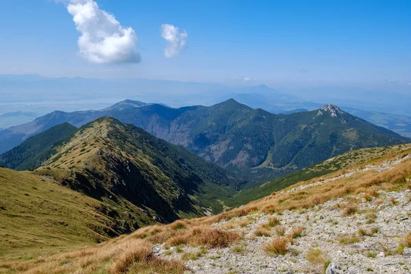 rocky mountain tops with hiking trails in autumn in Slovakian Tatra western Carpathian with blue sky and late grass on  hills. Empty rocks in bright daylight, far horizon for adventures.