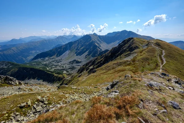 rocky mountain tops with hiking trails in autumn in Slovakian Tatra western Carpathian with blue sky and late grass on  hills. Empty rocks in bright daylight, far horizon for adventures.