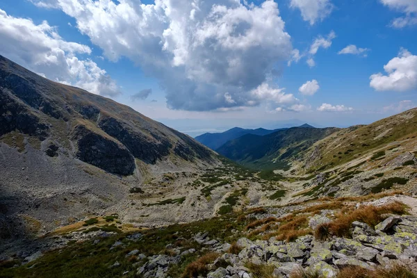 rocky mountain tops with hiking trails in autumn in Slovakian Tatra western Carpathian with blue sky and late grass on  hills. Empty rocks in bright daylight, far horizon for adventures.
