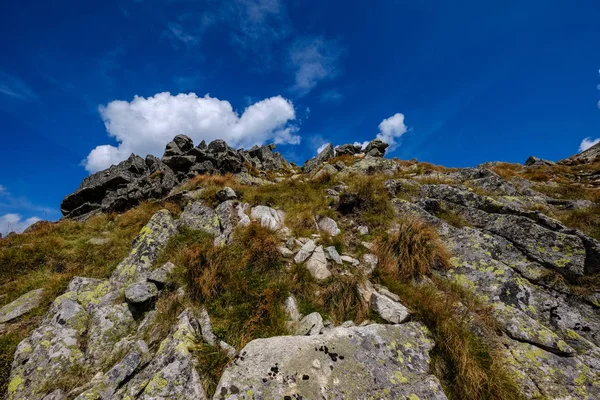 rocky mountain tops with hiking trails in autumn in Slovakian Tatra western Carpathian with blue sky and late grass on  hills. Empty rocks in bright daylight, far horizon for adventures.