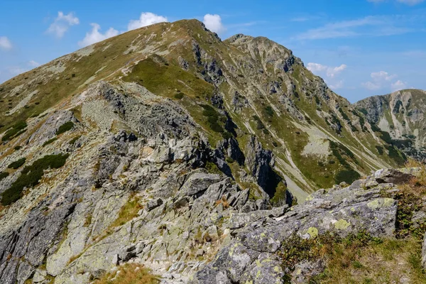 rocky mountain tops with hiking trails in autumn in Slovakian Tatra western Carpathian with blue sky and late grass on  hills. Empty rocks in bright daylight, far horizon for adventures.