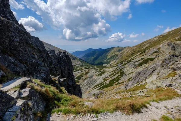 rocky mountain tops with hiking trails in autumn in Slovakian Tatra western Carpathian with blue sky and late grass on  hills. Empty rocks in bright daylight, far horizon for adventures.
