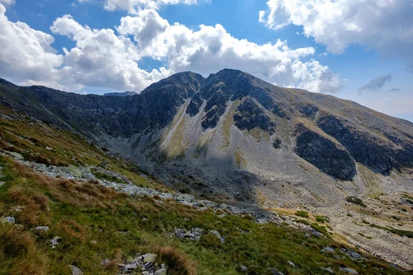 rocky mountain tops with hiking trails in autumn in Slovakian Tatra western Carpathian with blue sky and late grass on  hills. Empty rocks in bright daylight, far horizon for adventures.