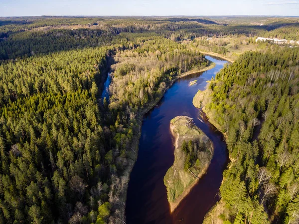 drone image. aerial view of rural area with fields and forests and water reflections in river in cloudy spring day. latvia