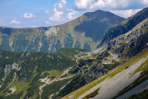 rocky mountain tops with hiking trails in autumn in Slovakian Tatra western Carpathian with blue sky and late grass on  hills. Empty rocks in bright daylight, far horizon for adventures.